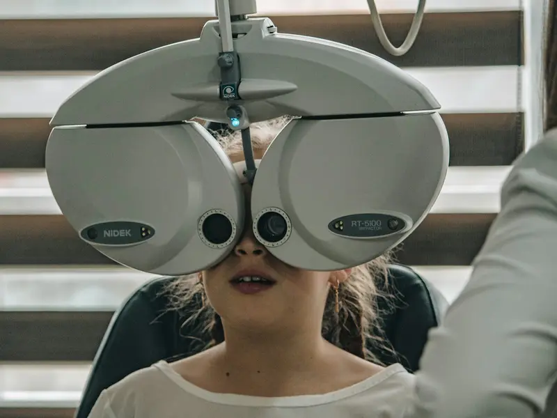 Enfant pendant un examen de la vue, derrière un réfracteur